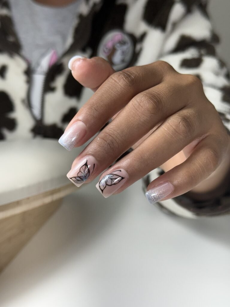 Hand with glitter butterfly nail design and russian manicure in Tampa, Florida.
