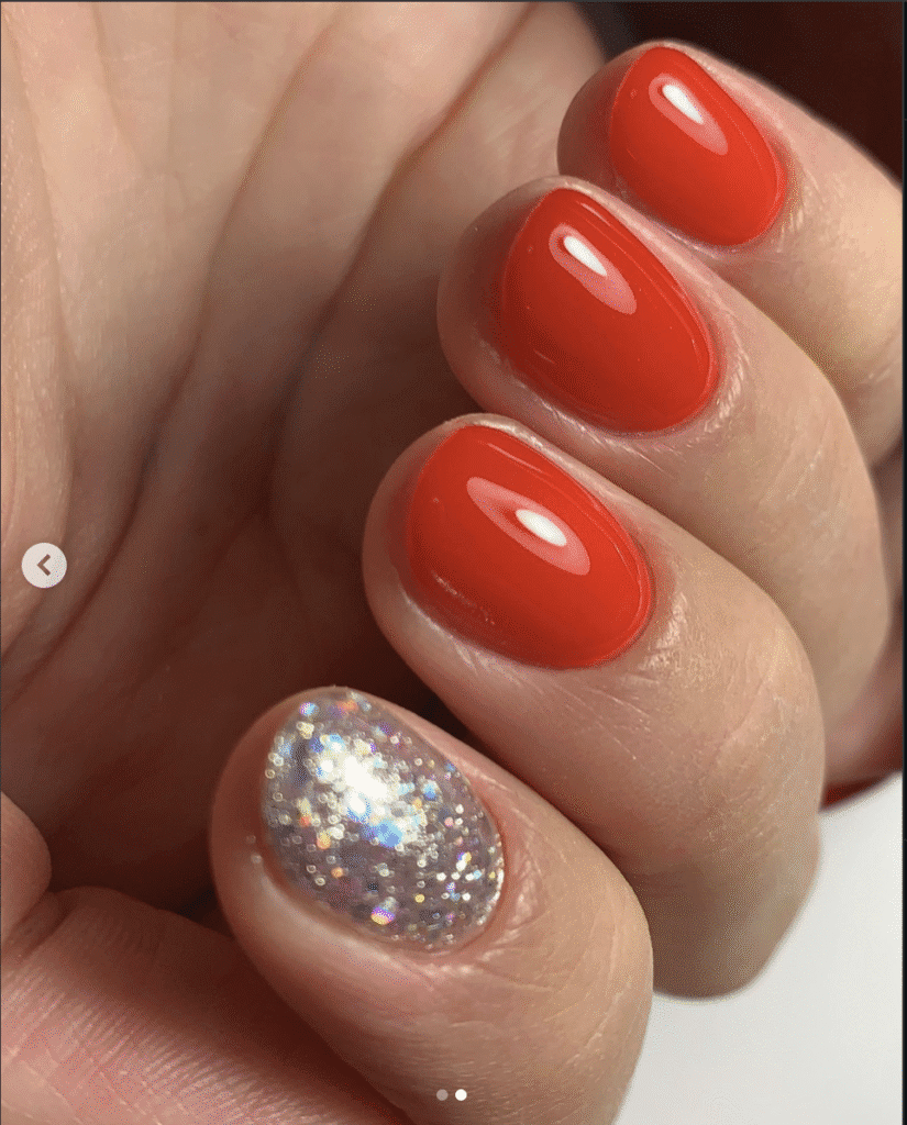 Builder gel manicure Tampa featuring glossy red nails with accent sparkle in natural light.