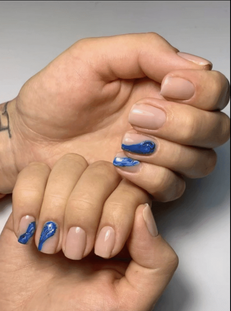 Hands with nude polish and blue accents created using russian nails technique in Tampa, Florida.