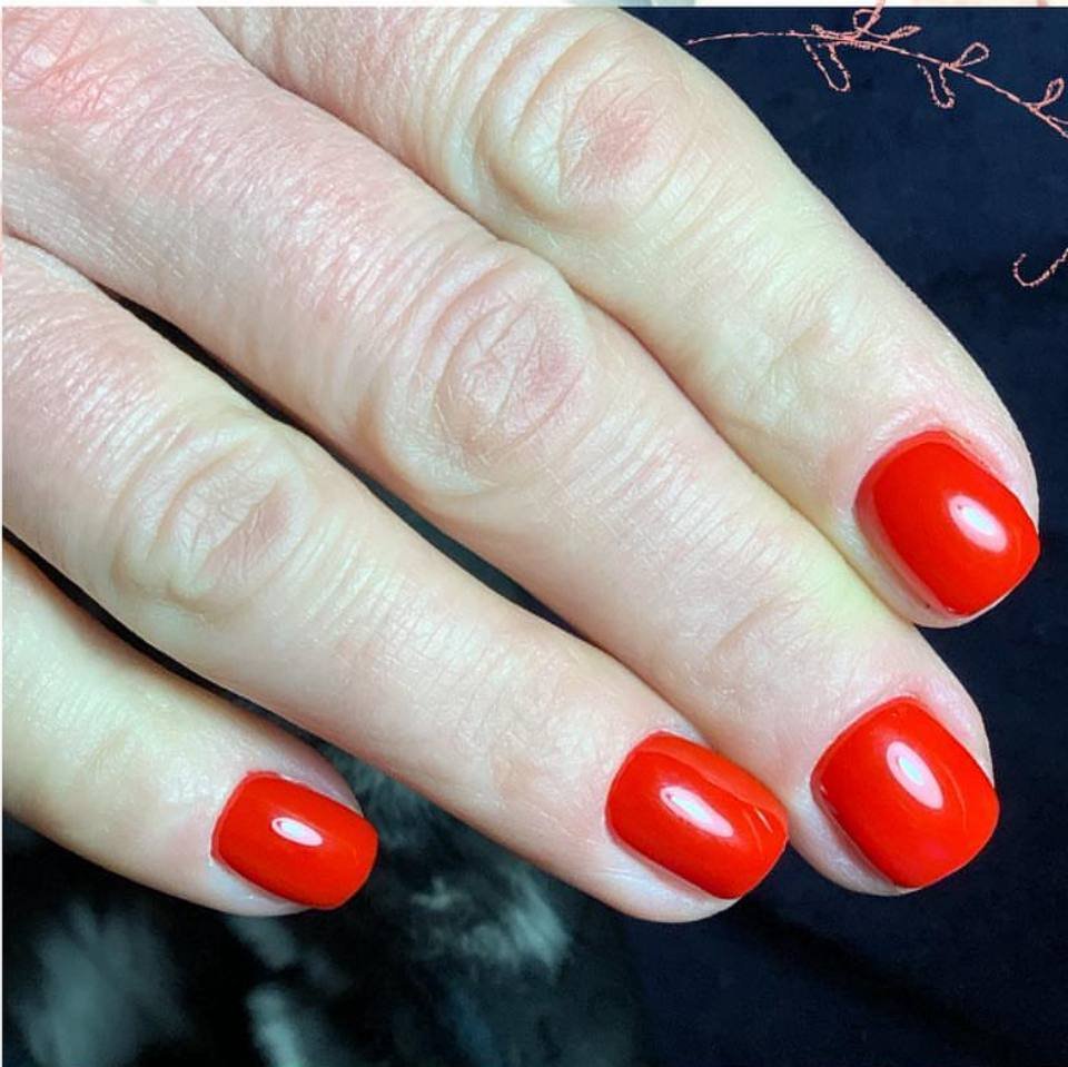 Glossy red nails from a european manicure near me in Tampa, Florida at Nail Boss Studio.