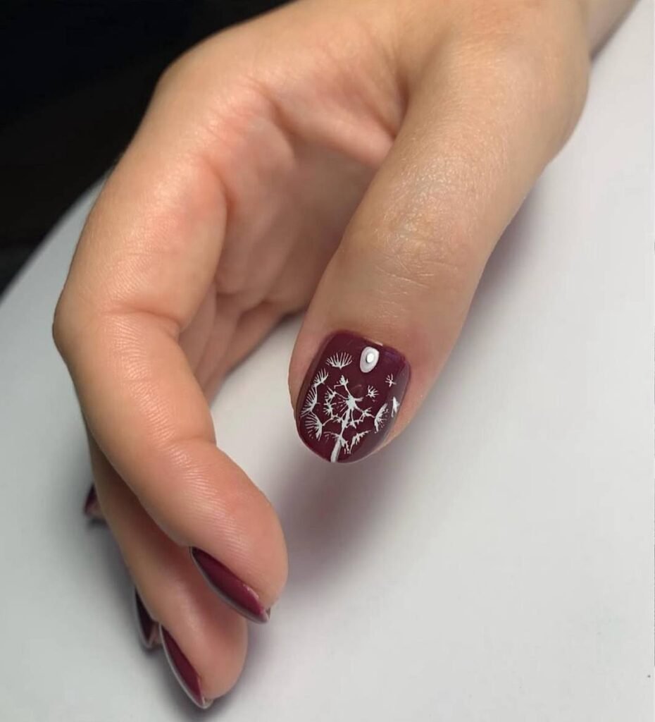 Deep burgundy manicure with delicate white botanical nail art created in a russian manicure salon in Tampa Florida.
