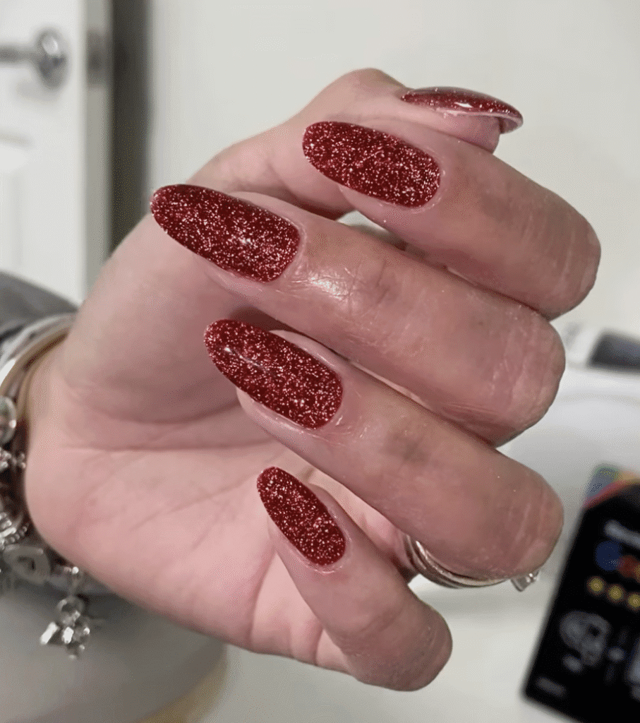 Elegant red sparkle builder gel manicure in Tampa Florida with almond-shaped nails and glossy finish