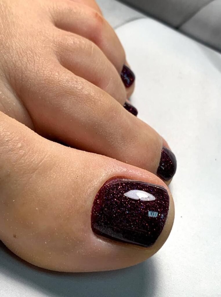 Close-up of a dry pedicure with glossy dark shimmer polish on toes in Tampa Florida