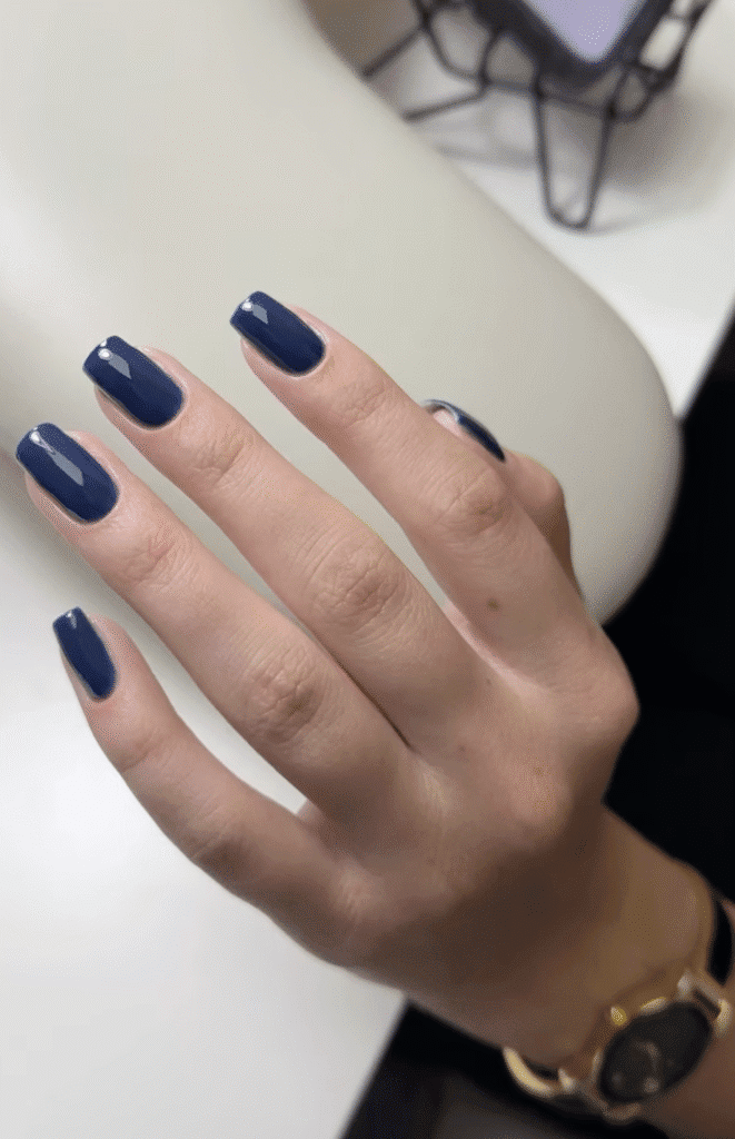 Glossy navy nails from a european manicure near me in Tampa, Florida with clean cuticle work and natural shape