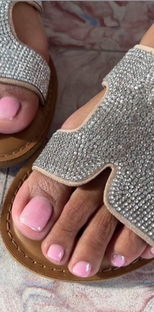 Soft pink gel pedicure Tampa on natural toenails with glossy finish in sandals