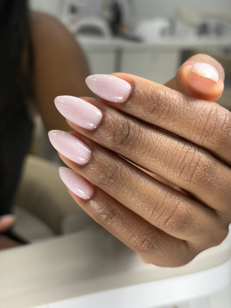 Soft pink almond-shaped nails with delicate shimmer showcasing russian manicures Tampa at a luxury nail studio in Tampa, Florida.