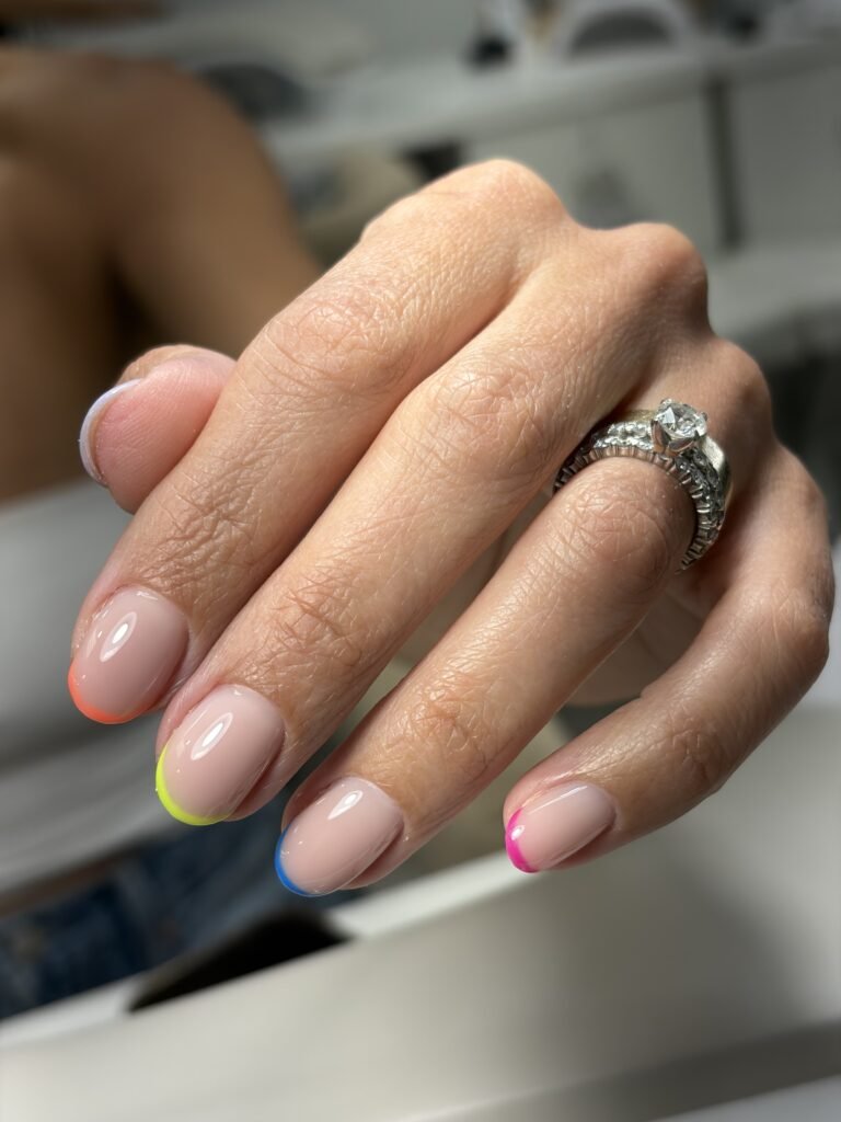 Elegant dry manicure with glossy nude nails and colorful neon French tips in Tampa, Florida.