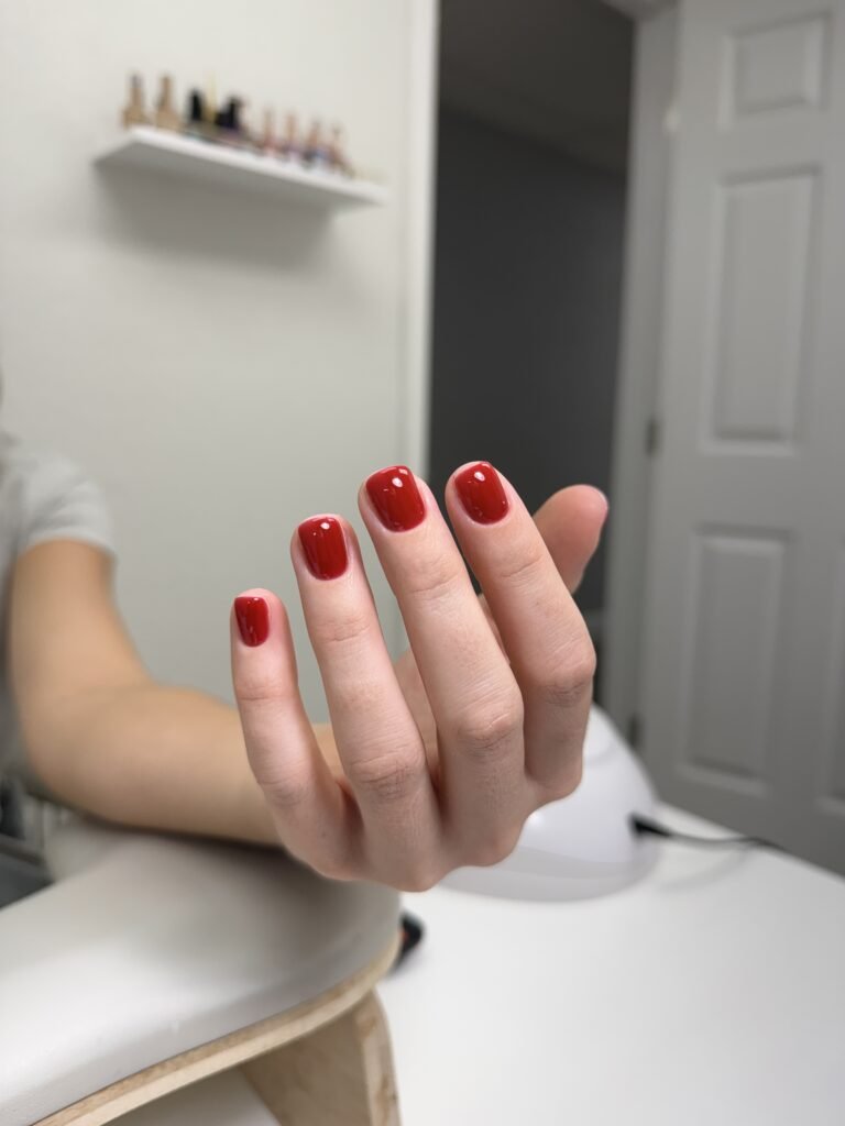 Fresh glossy red european manicure on natural short nails at Nail Boss Studio Tampa, Florida.