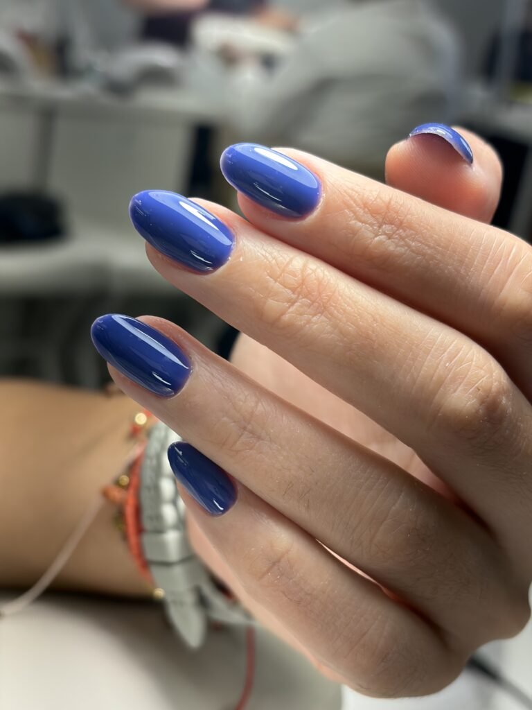Glossy blue european manicure on natural almond-shaped nails at Nail Boss Studio in Tampa, Florida.