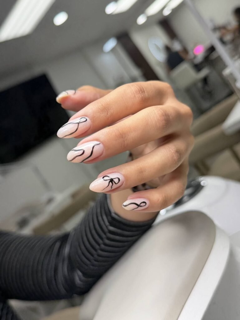 Elegant almond-shaped nails with delicate ribbon nail art showcasing russian manicures Tampa at Nail Boss Studio in Tampa, Florida.